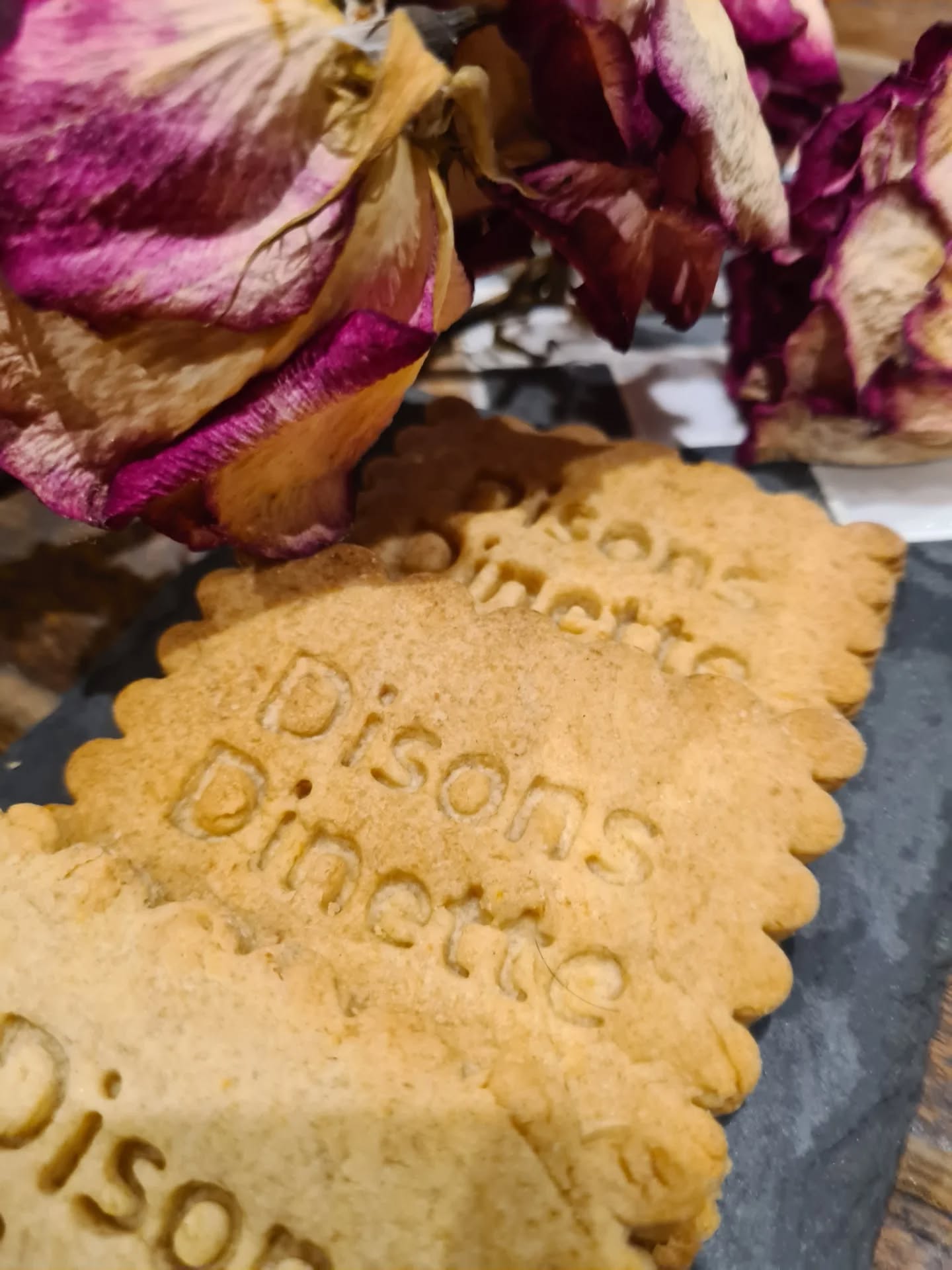 Sablés tamponnés du logo Disons Dinette, posés près de roses séchées