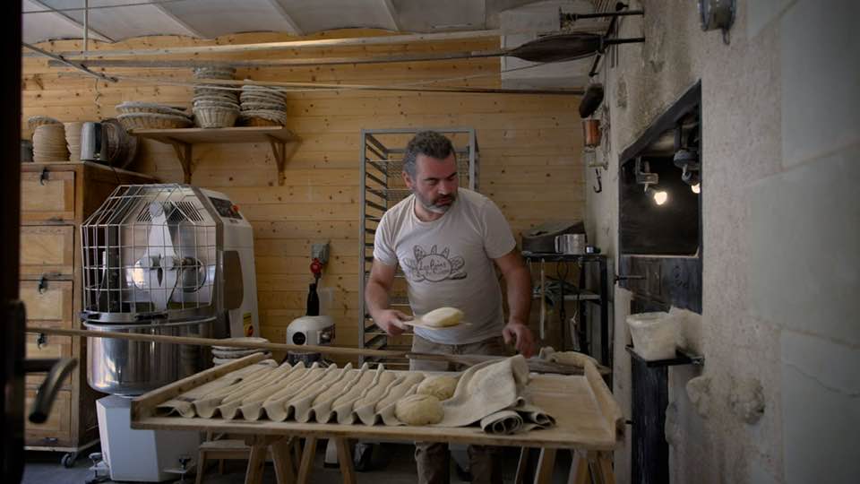Boulanger façonnant des pains avant cuisson au four à bois