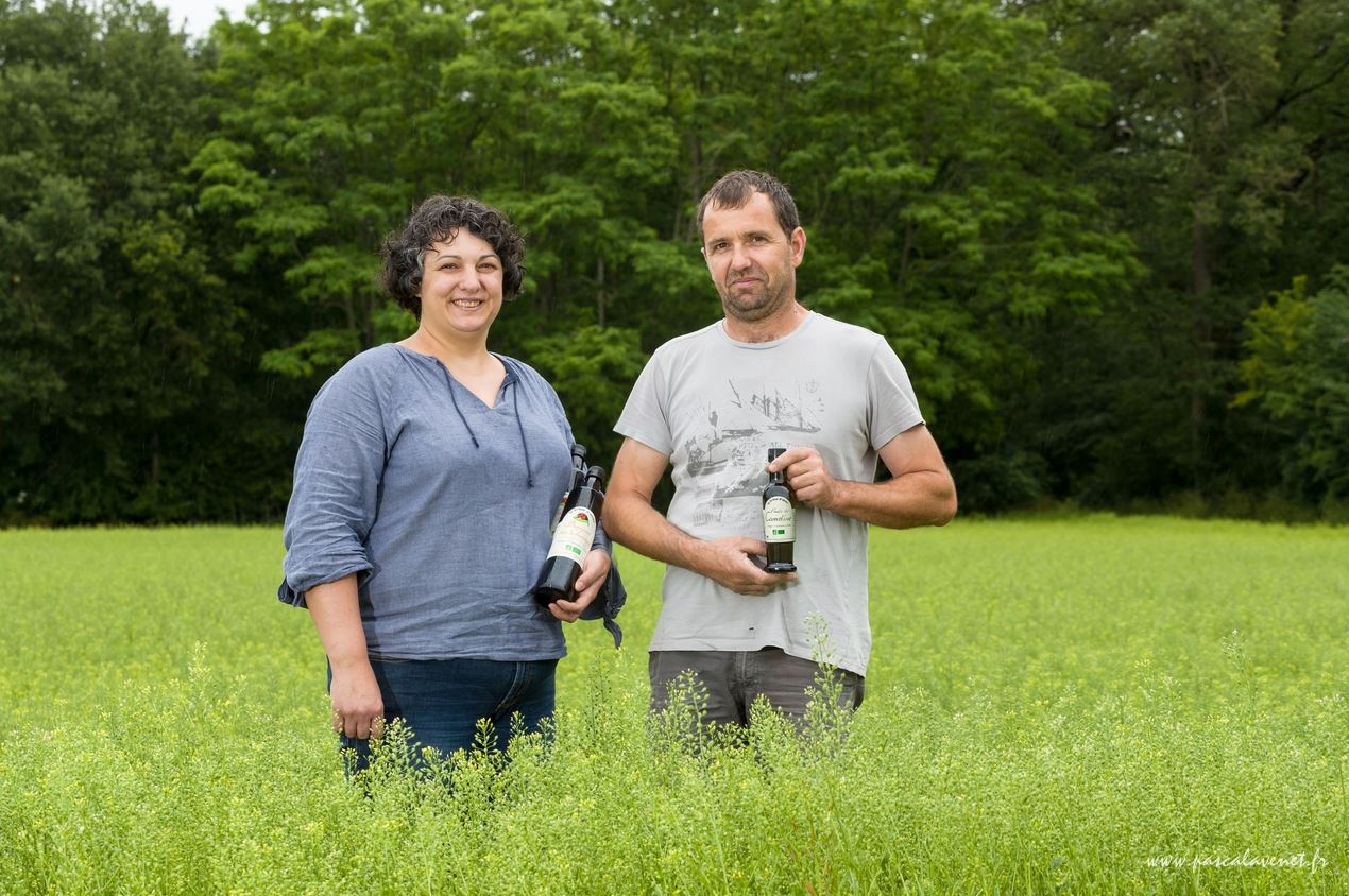 Les producteurs de Ti Bio'aire tiennent des bouteilles d'huile de cameline dans un champ